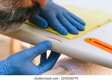 Surfer repairing a blow to a surfboard. - Powered by Shutterstock