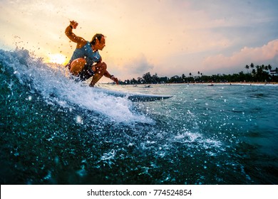 Surfer rides the ocean wave during sunset with lots of splashes. Active lifestyle and extreme sport concept