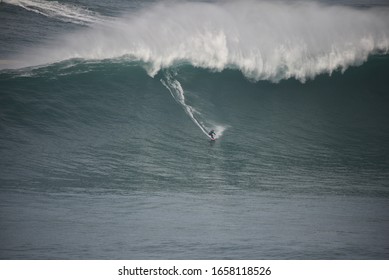 A Surfer Riding A Huge Wave In Nazare, Portugal. 