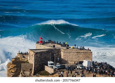Surfer riding huge wave near the Fort of Sao Miguel Arcanjo Lighthouse in Nazare, Portugal. Nazare is famously known for having the biggest waves in the world.