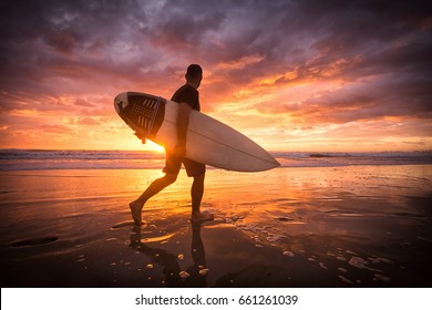 Surfer running on the beach at sunrise with reflections - Powered by Shutterstock