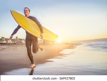 Surfer Running On The Beach At Sunset