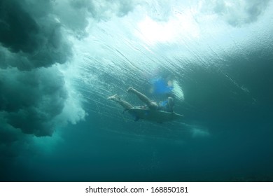 A surfer safely duck dives under a wave in Fiji