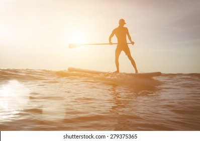 surfer silhouette at sunset.image with lens flare included for an artistic touch. concept about sport, surf, vacations and people