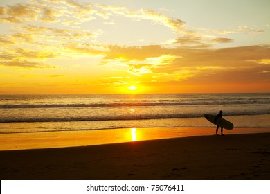 Surfer standing on the beach during a beautiful sunrise