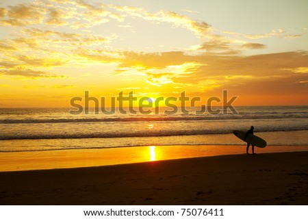 Surfer standing on the beach during a beautiful sunrise