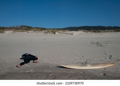 A surfer stretches before entering the sea at Arda beach in Portugal - Powered by Shutterstock