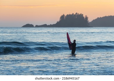 Surfer With Surf Board At Sunset On Chesterman Beach, Tofino, Vancouver Island, Canada.