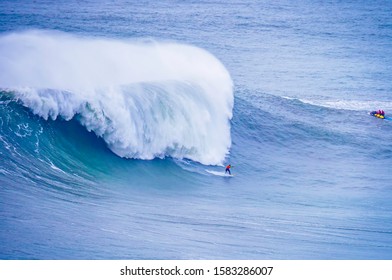 Surfer Surfing Massive Waves At Nazare Portugal