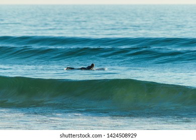 Surfer Swimming Behind Wild Waves