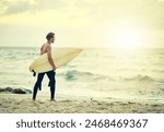 Surfer, walking and man on beach at sunset for adventure in summer, holiday or travel in vacation. Person, surfing and search for waves in Australia water, ocean and exercise in sea with board