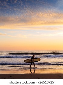 Surfer Walking On The Beach At Sunset In San Diego CA