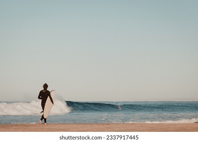 Surfer walking out to empty point break