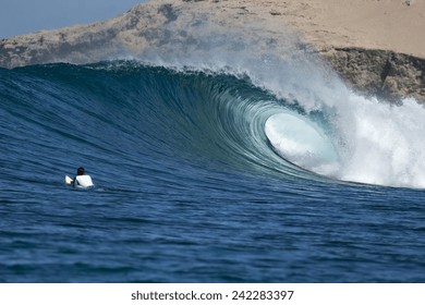 A surfer watches a tube break on an ocean wave.