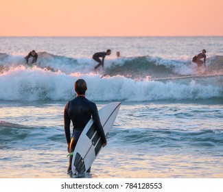 Surfer Watching His Friends Surfing From The Shore 