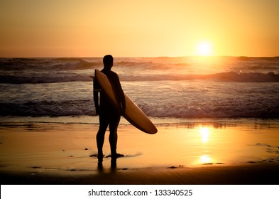Surfer watching the waves at sunset in Portugal.