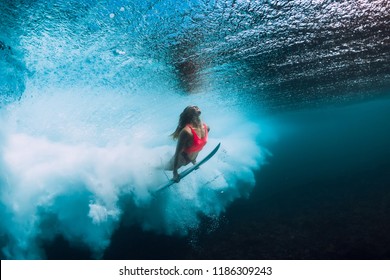 Surfer woman with surfboard dive underwater with under ocean wave.