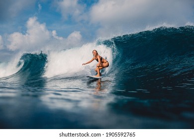 Surfer woman at surfboard on barrel wave. Sporty woman in ocean during surfing.