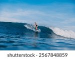 Surfer woman at surfboard rides on ocean wave. Young sporty woman during surfing.