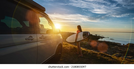 Surfergirl walking near her mini van and looking on the ocean at summer sunset  with a surfboard on her side - selective focus - Shutterstock ID 2180855097
