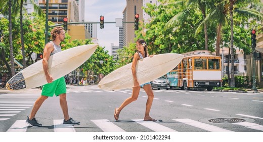 Surfers going surfing in Waikiki beach, Honolulu, Hawaii. USA summer travel vacation happy couple friends walking crossing city street carrying surfboards. Asian woman, Caucasian young man. - Powered by Shutterstock