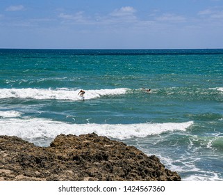 Surfers Off A Rocky Florida Beach On Hutchinson Island In Summer.