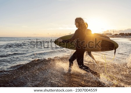 Surfers running into the water with surfboards.