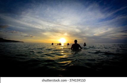 Surfers Sitting In Front Of The Sunset