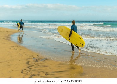 Surfers with surfboards on the sandy ocean - Powered by Shutterstock