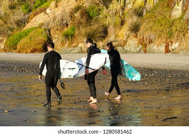Surfers in wet suit holding surfboard on the beach. Surfers going to the water, on San Elijo State Beach in Cardiff, California, located in San Diego County. USA. 01/04/2019