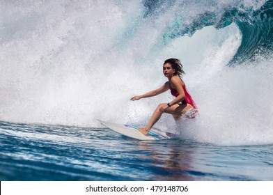 Surfing girl riding a giant ocean wave. Blue ocean water crashing with splashes and drops. Water sport activity 