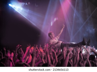 Surfing on a wave of praise. A stage diver being carried across the audience at a rock concert. - Shutterstock ID 2134656113