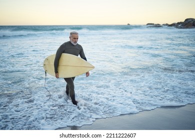 Surfing, surfboard and senior man on beach for water sports while walking on adventure after riding sea waves on a overcast day. Surfer male at ocean for surf journey or travel vacation in Bali - Powered by Shutterstock