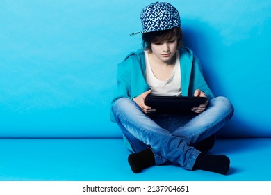 Surfing the web on his tablet. A young boy sitting on his digital tablet in the studio.