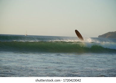 Surfing Wipe Out On Tamarindo Beach In Costa Rica With Surf Board In Mid Air