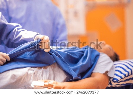 Surgeon and assistant during operation pulling up the sheet