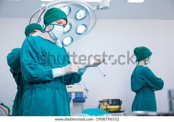 Surgeon in blue surgical gown binds
the mouthguard for an emergency. The surgeon is wearing gloves in
an operating room equipped with modern medical
equipment.
