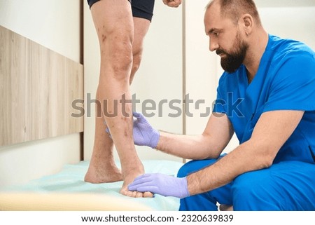 Surgeon cardiologist carefully examining veins on patient legs