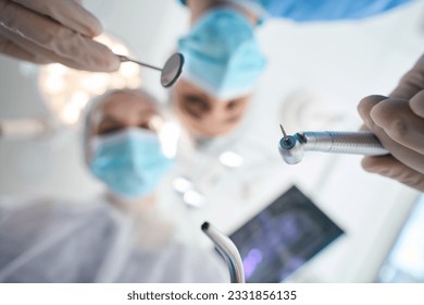 Surgeon dentist with assistant at the workplace in operating room - Powered by Shutterstock