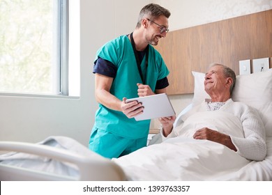 Surgeon With Digital Tablet Visiting Senior Male Patient In Hospital Bed In Geriatric Unit