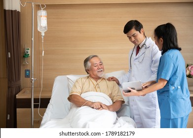 Surgeon Doctor With Digital Tablet Visiting Senior Male Patient In Hospital Bed At Geriatric Unit