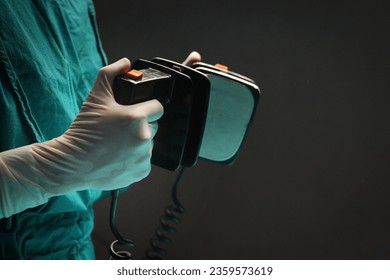 Surgeon doctor hand hold defibrillator to pump chest heart patient to save life sick people in operating room at hospital, surgical team using equipment to do surgery. healthcare and medical concept. - Powered by Shutterstock