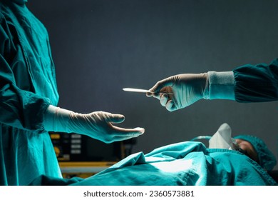 Surgeon doctor holding surgical scalpel and passing surgical equipment to each other in operating room at hospital. Professional surgical team operating surgery patient, healthcare and medical concept - Powered by Shutterstock