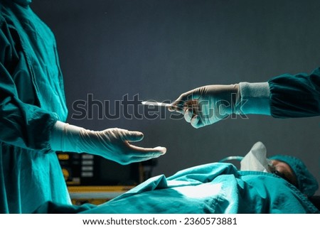 Surgeon doctor holding surgical scalpel and passing surgical equipment to each other in operating room at hospital. Professional surgical team operating surgery patient, healthcare and medical concept