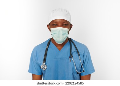 Surgeon Doctor Man In Blue Coat White Cap And Surgeon Mask With Stethoscope Isolated On White Background. Focused Adult African American Practicing Surgeon Portrait, Concentrated Look