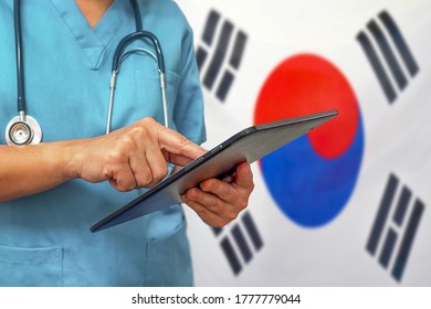 Surgeon Or Doctor Using A Digital Tablet On The Background Of The South Korea Flag. Medical Equipment Or Medical Network, Technology And Diagnostics In South Korea.