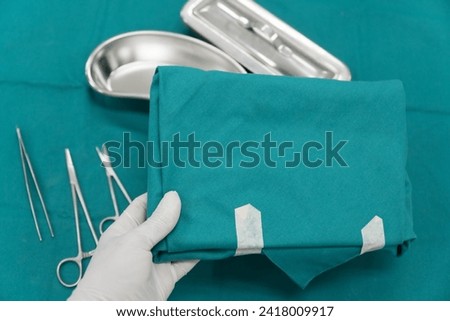 Surgeon doctor's hand with hygiene glove taking surgical set and medical equipment on green surgical tray inside operating room.Sterile surgical instrument tool equipment for surgery.Infection control