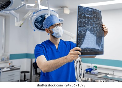 Surgeon Examining X-ray in Operating Room. A surgeon in scrubs and a face mask examines an x-ray in an operating room. - Powered by Shutterstock