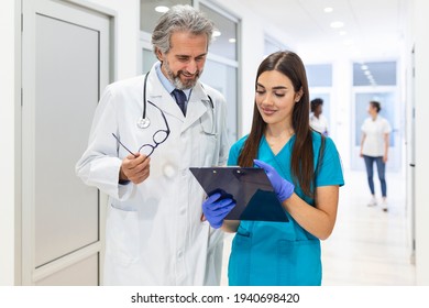 Surgeon and Female Doctor Walk Through Hospital Hallway, They Consult Digital Tablet Computer while Talking about Patient's Health. Modern Bright Hospital with Professional Staff. - Powered by Shutterstock