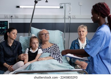 Surgeon filling out necessary paperwork to admit sick elderly man for medical intervention at operating room. Chronically ill grandfather being cared by african american doctor. - Powered by Shutterstock